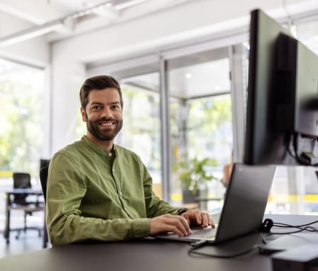 Man smiling and typing on computer in office