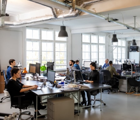 People coding on separate computers in a room