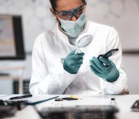 Woman using magnifying glass to inspect computer hardware