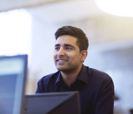 Man looking up from computer screen, smiling