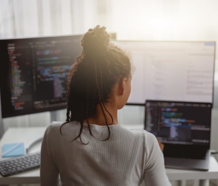 Woman typing on laptop with double monitors