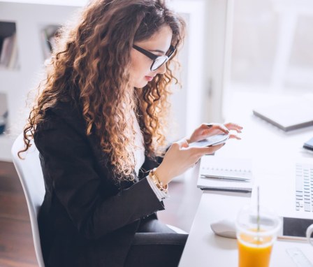 Professional woman using a smartphone at a work desk