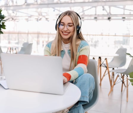 Young woman working on laptop wearing headphones